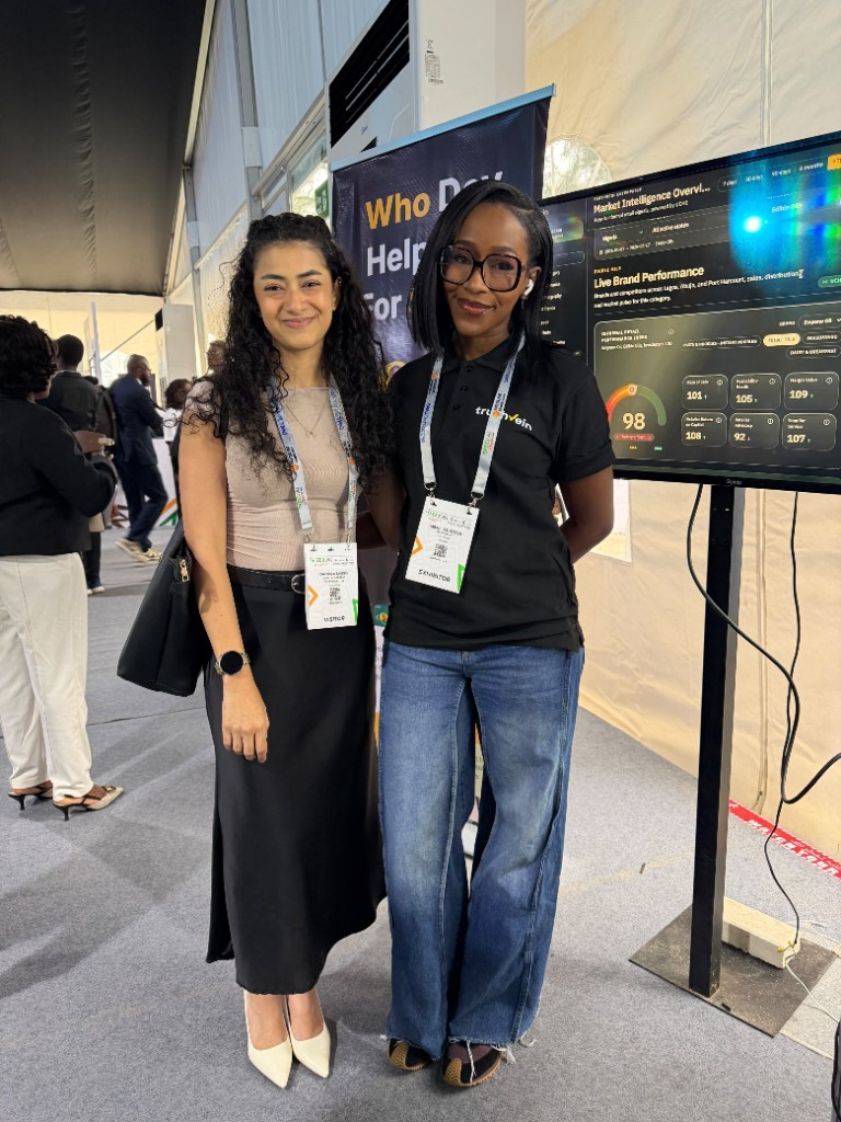 A visitor with a TruthVein exhibitor at the stand, the live dashboard beside them